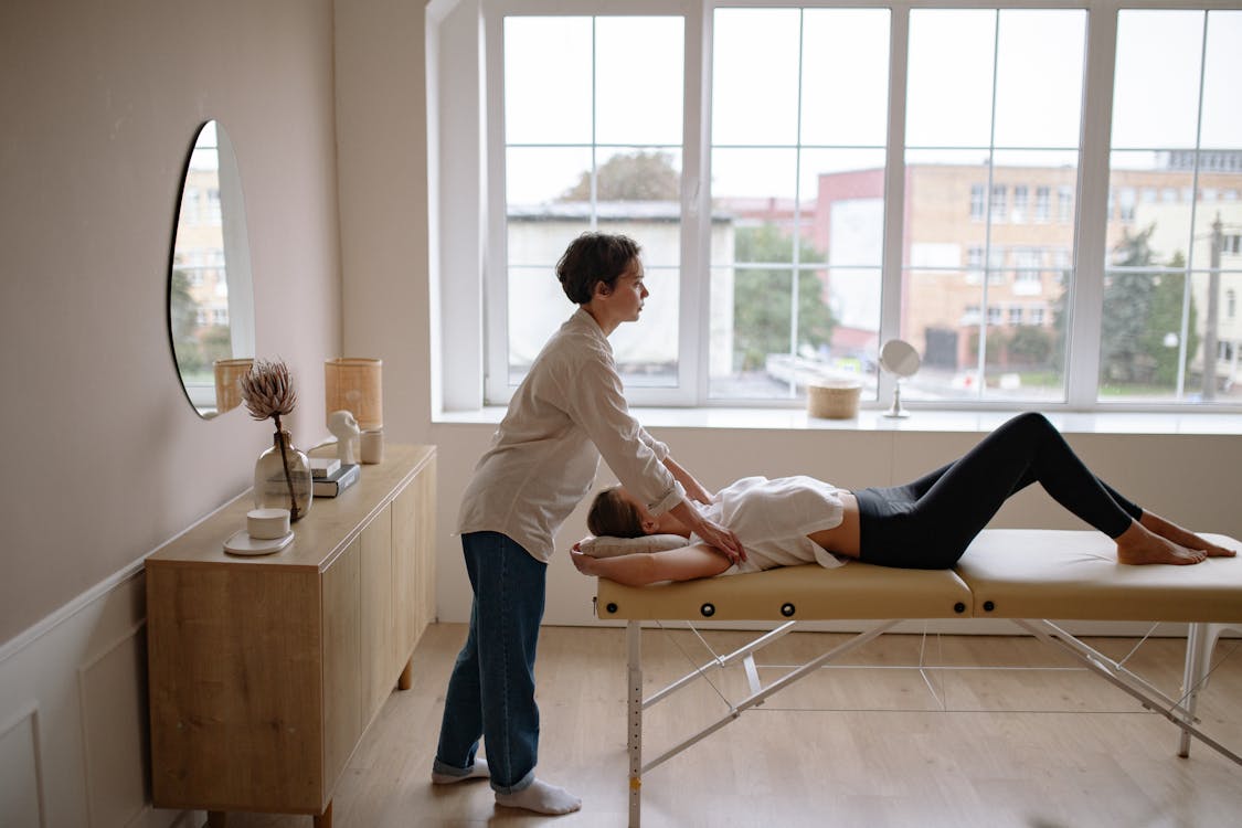 Free A Massage Therapist Massaging a Woman on a Massage Table Stock Photo