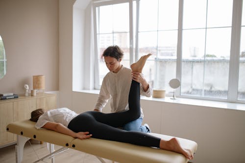 Free A Massage Therapist Holding a Woman's Leg Up Stock Photo