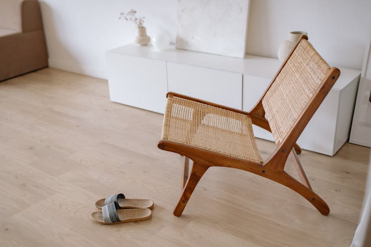 A Pair Of Slippers Near A Brown Woven Wooden Chair 