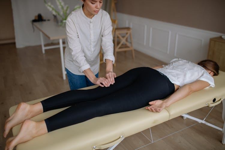 Woman In Black Leggings Lying On Massage Table