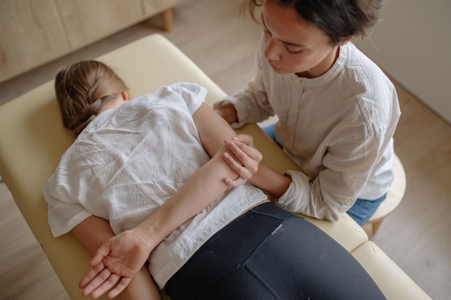 Therapist applying focused pressure to a patient's shoulder and arm