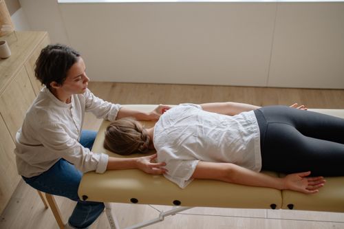 Free A therapist performs a chiropractic adjustment on a woman lying on a treatment table indoors. Stock Photo