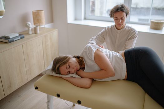 A woman receives a therapeutic massage from a specialist indoors.