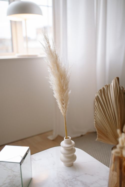 Free Stylish minimalist interior featuring a ceramic vase with pampas grass on a marble table. Stock Photo