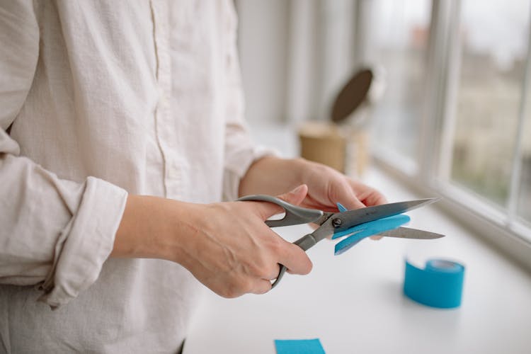 Person Holding Scissors And Cutting Paper