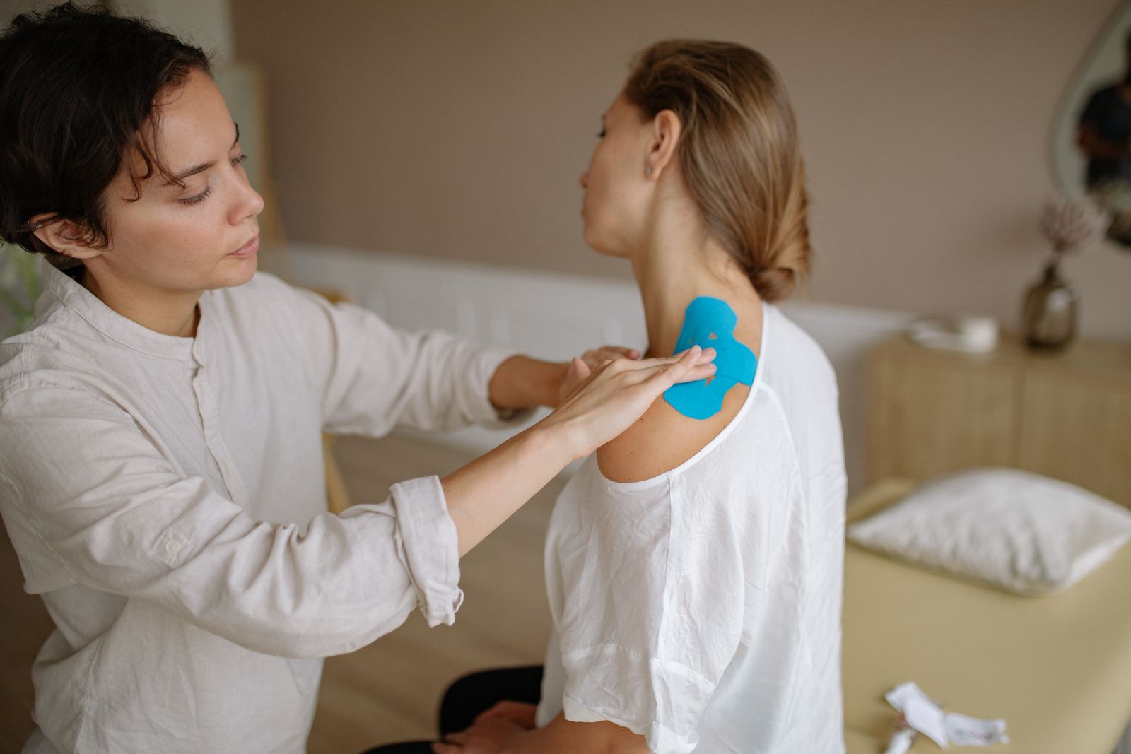 Clinician applying shoulder support tape, matching shoulder brace and shoulder support selection. Photo: Pexels.
