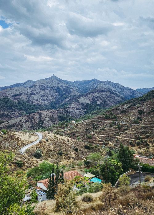Free Explore a serene landscape with a winding road and distant mountains under a cloudy sky. Stock Photo