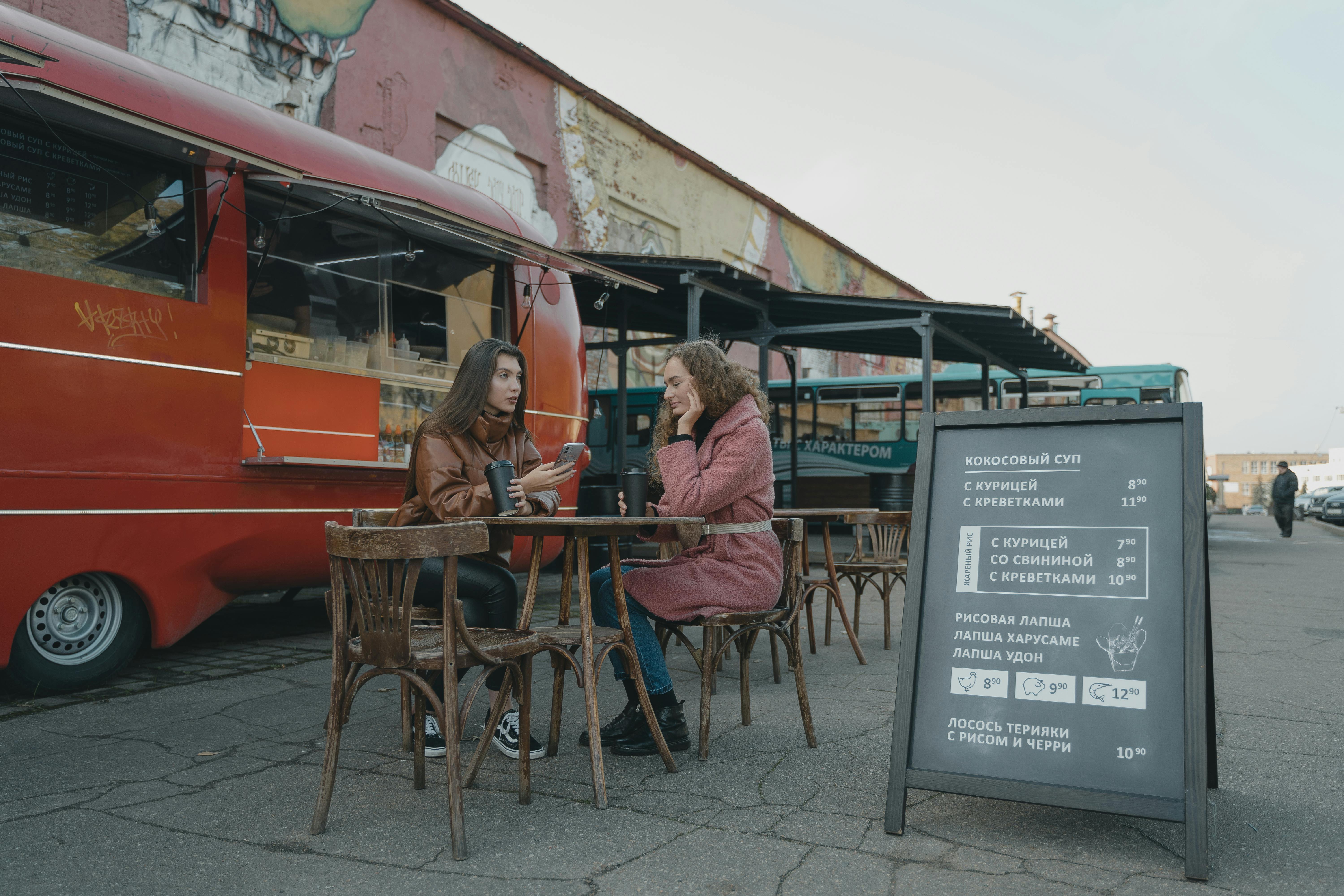 woman in brown jacket sitting beside woman in pink jacket