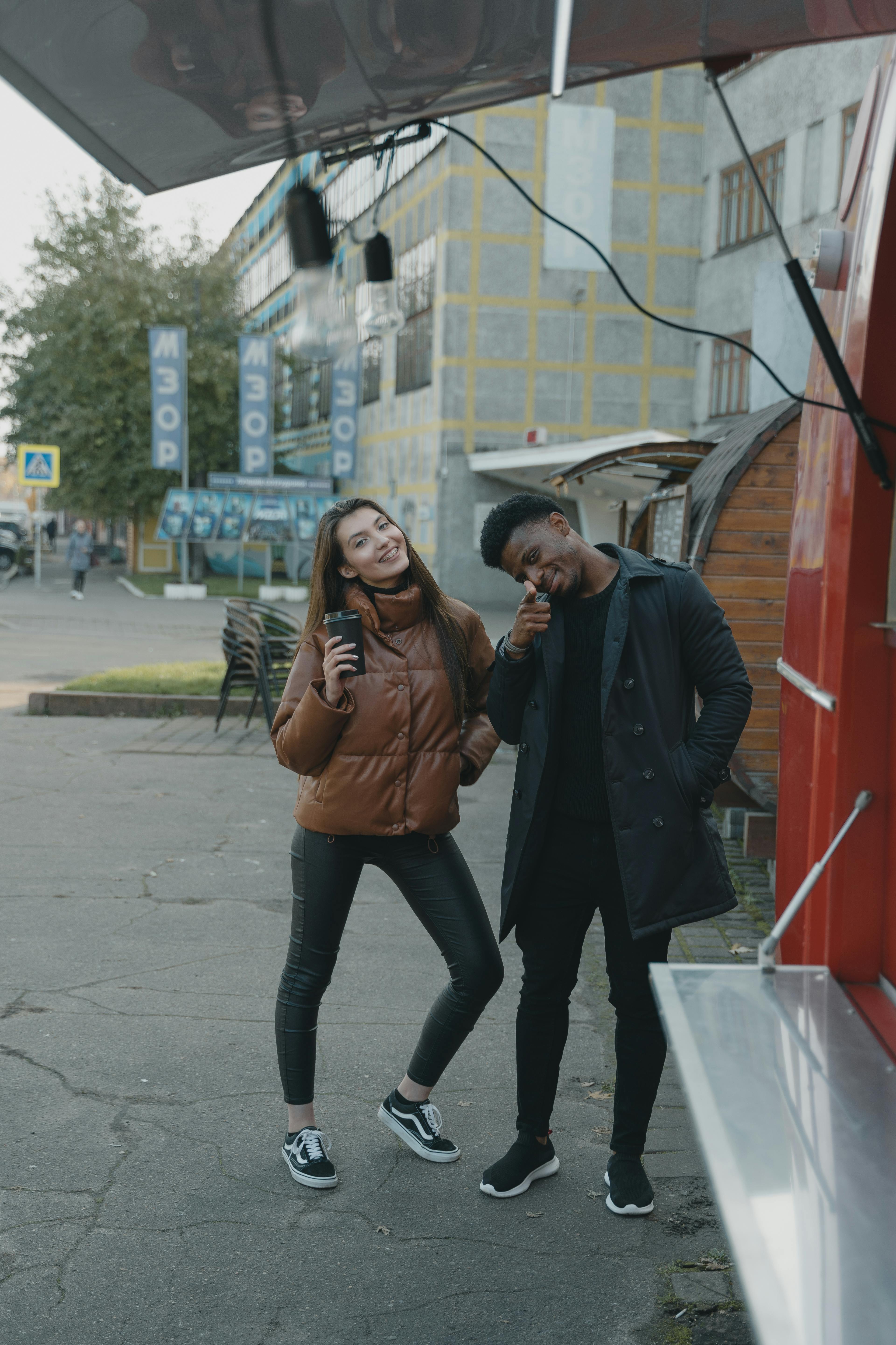Free Smiling friends with coffee outdoors by a food truck, capturing urban lifestyle vibes. Stock Photo