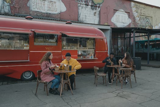 A group of friends enjoying casual dining outside a vintage food truck with vibrant street art.