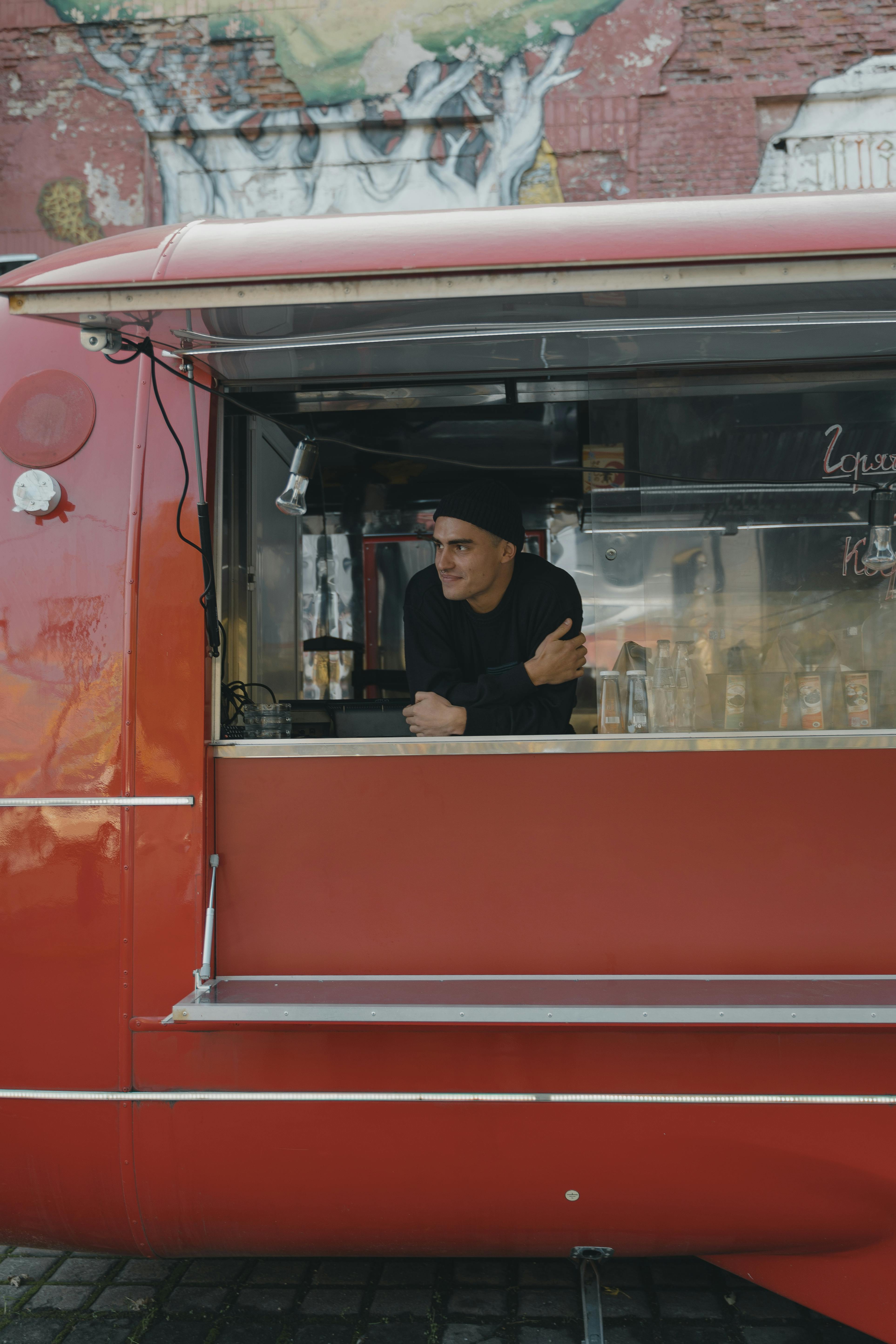 Free A man leans on a food truck counter, showcasing a street food small business. Stock Photo