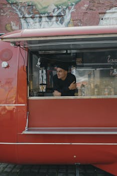 A man leans on a food truck counter, showcasing a street food small business.