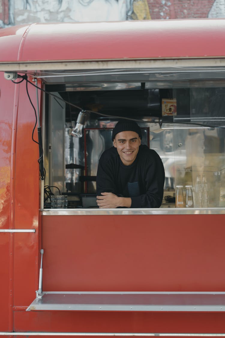 Man In Black Long Sleeve Shirt Standing Inside Red Van Smiling