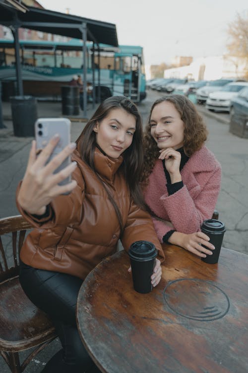 Free Women Wearing Jacket Having Coffee and Taking Selfie Stock Photo