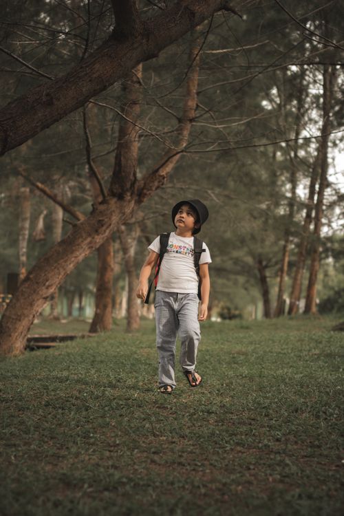 Free A young boy wearing a bucket hat walks through a lush park in Batam, Indonesia. Stock Photo