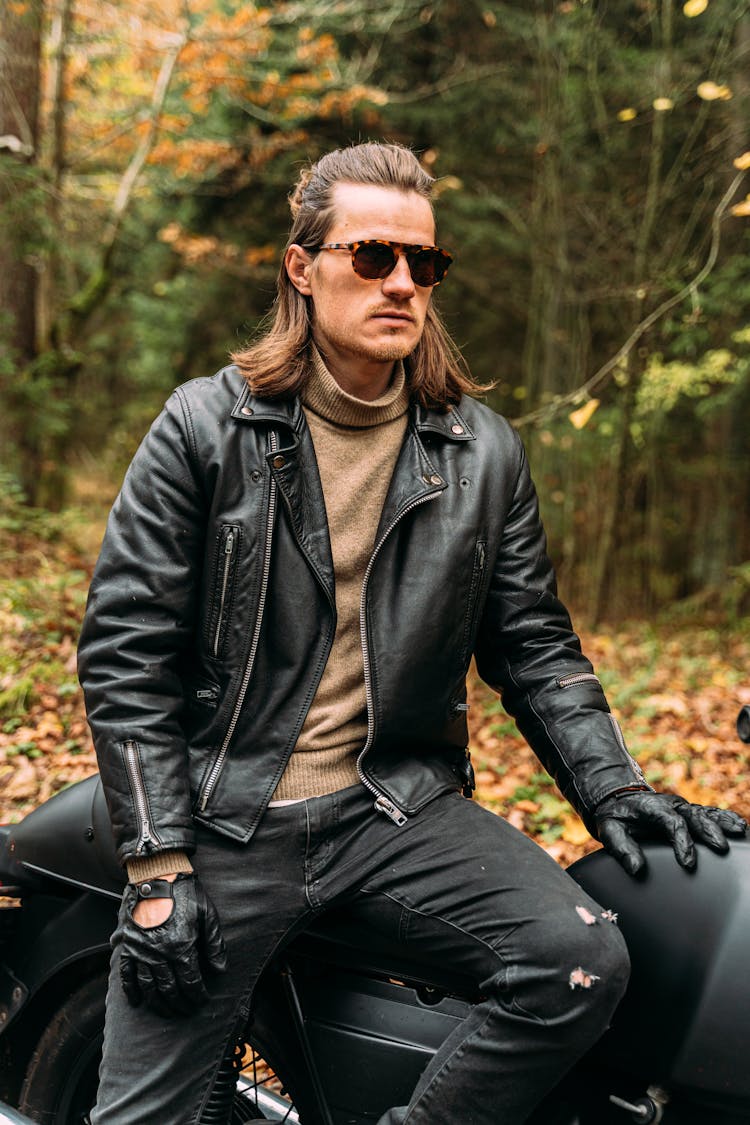 A Man In Black Leather Jacket Sitting On A Parked Motorcycle