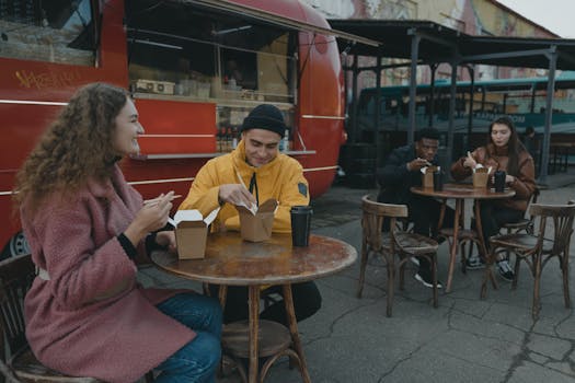 Friends enjoy a meal at an outdoor food truck area, promoting social dining.