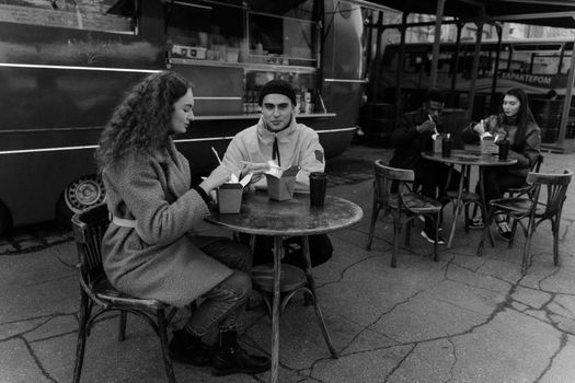 Group of friends enjoying street food at a food truck on a city street in grayscale.