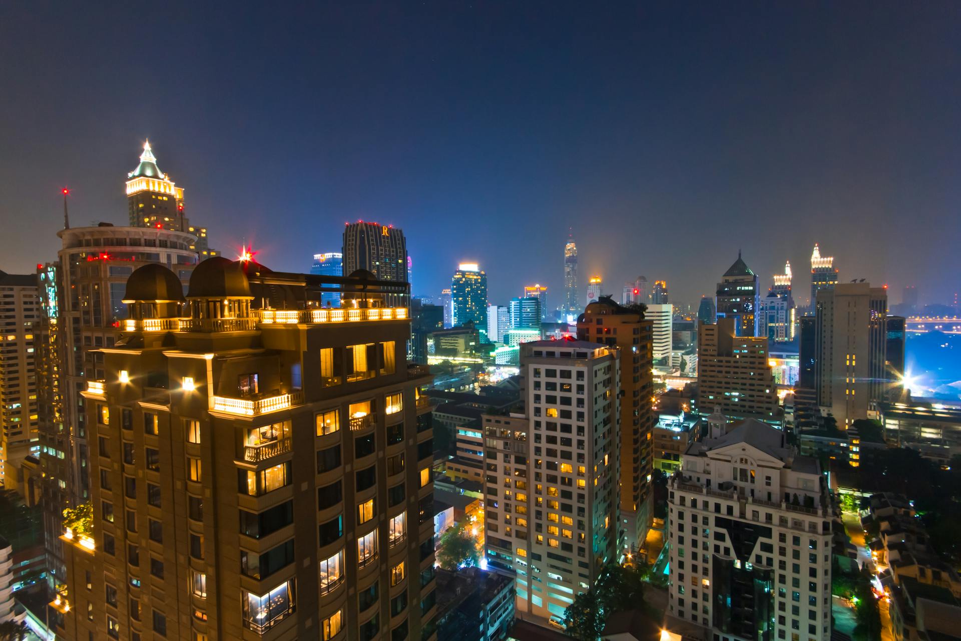 Illuminated city skyline at night with modern architecture and vivid lights.