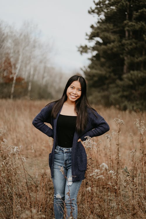 A Woman in Black Cardigan Standing in the Grass Field