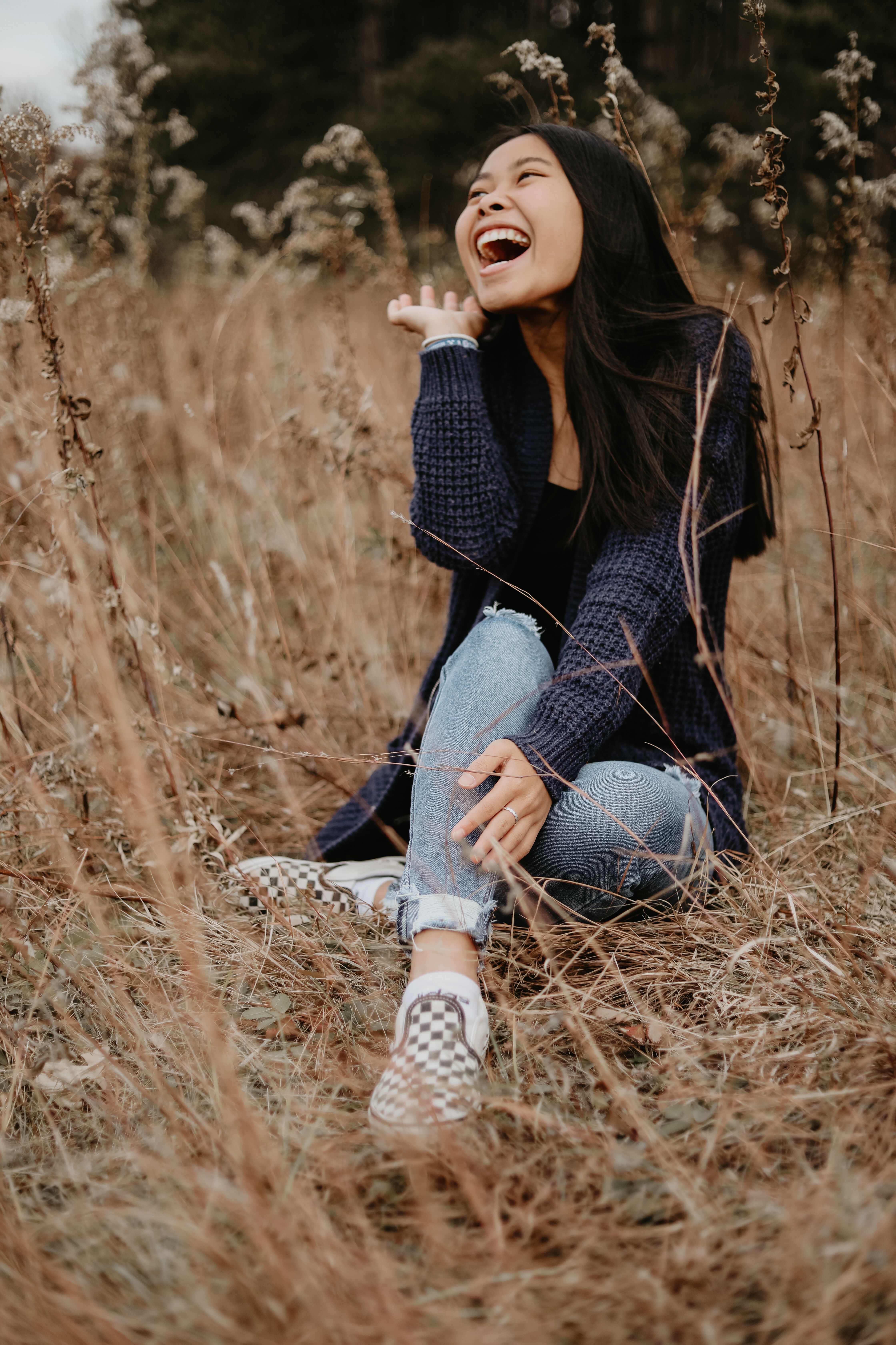 亚洲妇女坐在草地上，享受户外活动时开怀大笑