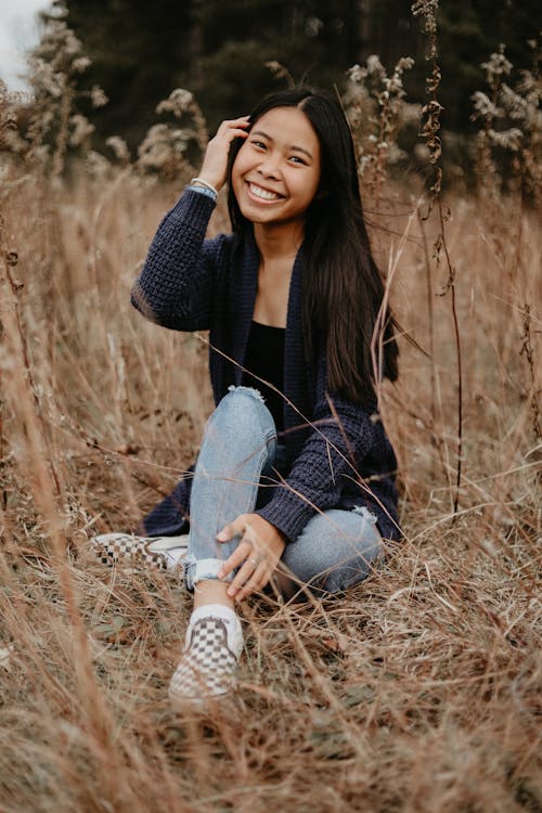 A Smiling Young Woman Sitting on Grass