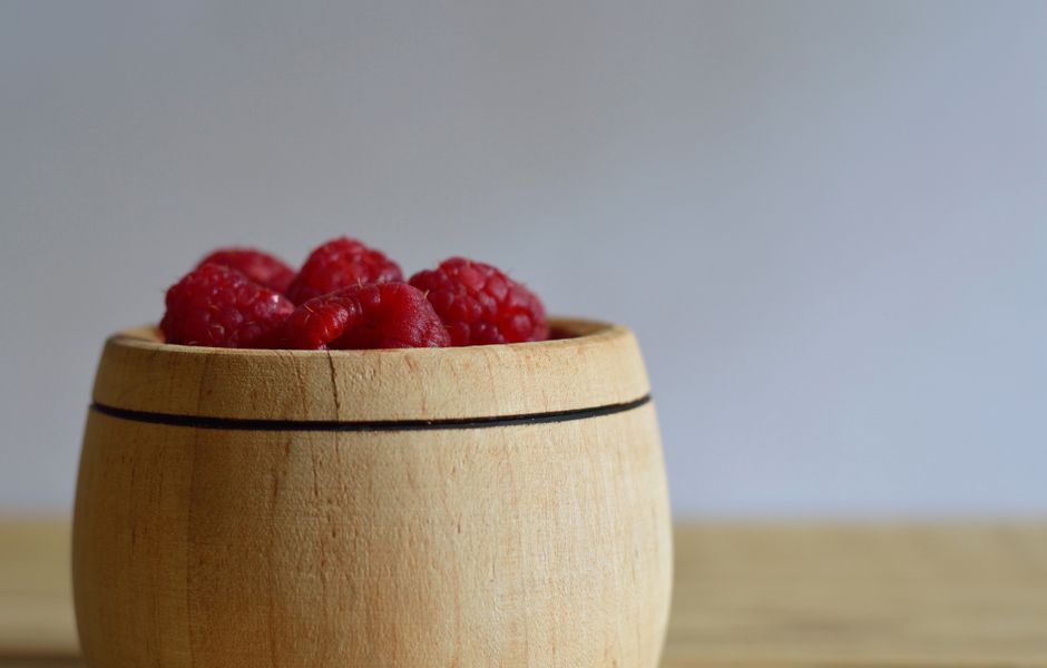 Macro shot of fresh raspberries in a rustic wooden bowl, perfect for food photography.