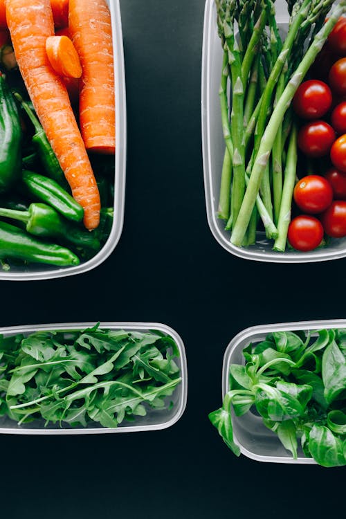 Fresh Vegetables in Plastic Containers over a Black Surface