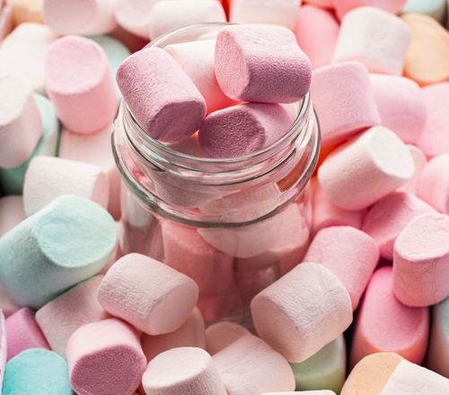Free Pastel colored marshmallows spilling from a glass jar, close-up view. Soft and fluffy texture. Stock Photo