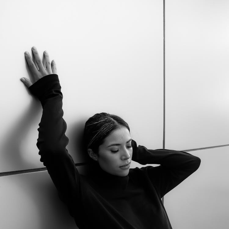 Black And White Photo Of A Beautiful Woman Leaning On The Wall