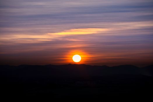 Vibrant sunset over Campo de Criptana's hills, capturing dramatic evening hues.