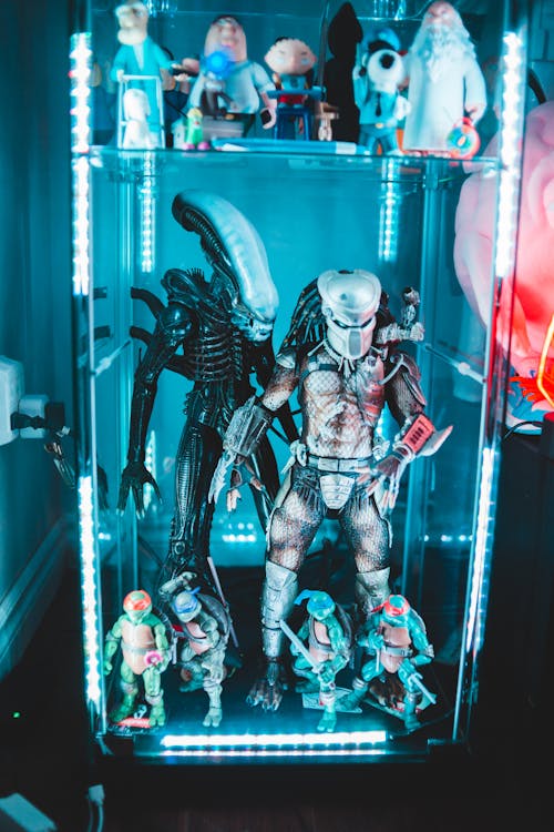 Figurines from movie placed in glass case with blue illumination in dark room