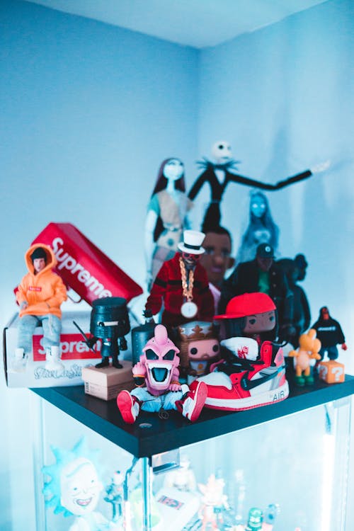 Creative figurines of different characters of cartoons and rappers placed on glass cabinet