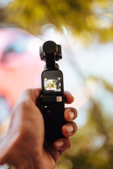 Crop male using modern stabilizer for smartphone to taking photo of tree in forest