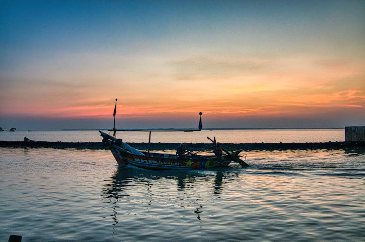 Boat On Ocean Near Dock Under Bright Sky At Night