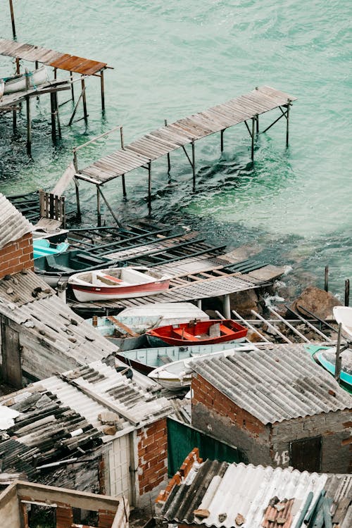 From above of traditional small boats moored near aged wooden pier in harbor of Arraial do Cabo on sunny day