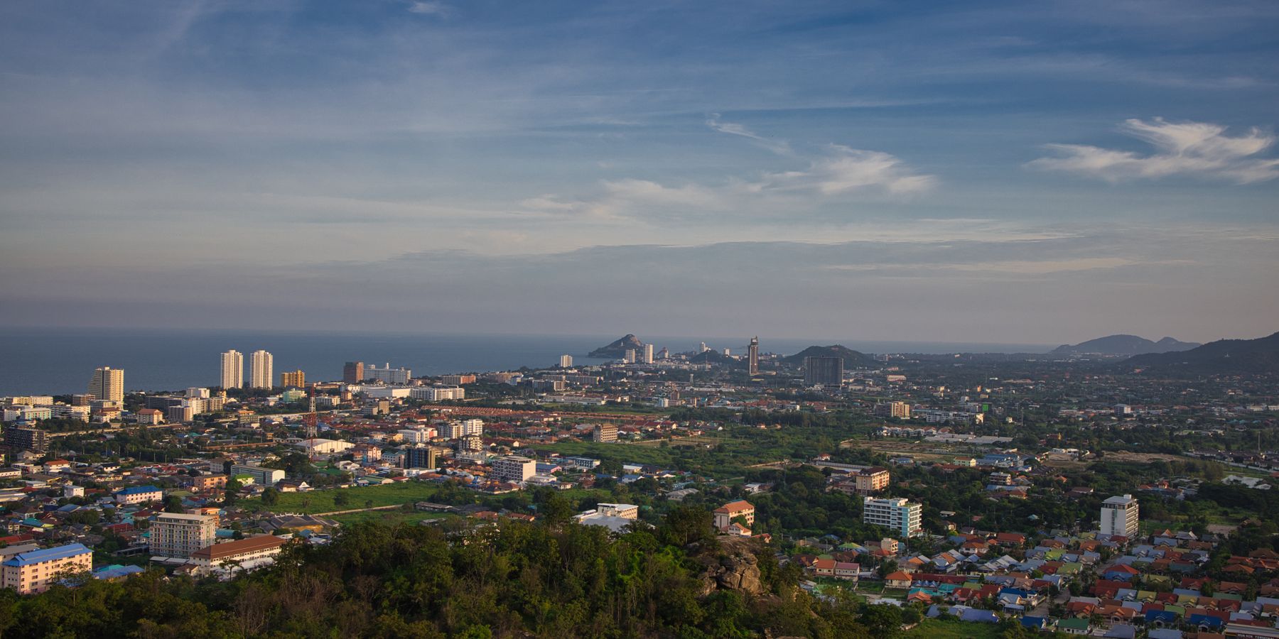 Panoramic aerial view of Hua Hin, Thailand with cityscape and ocean in the distance.