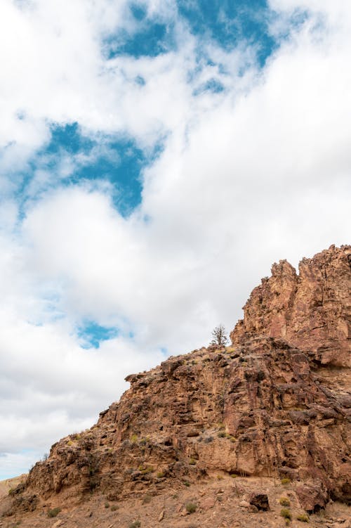 From below of rough rocky terrain located in highlands under cloudy blue sky in daylight