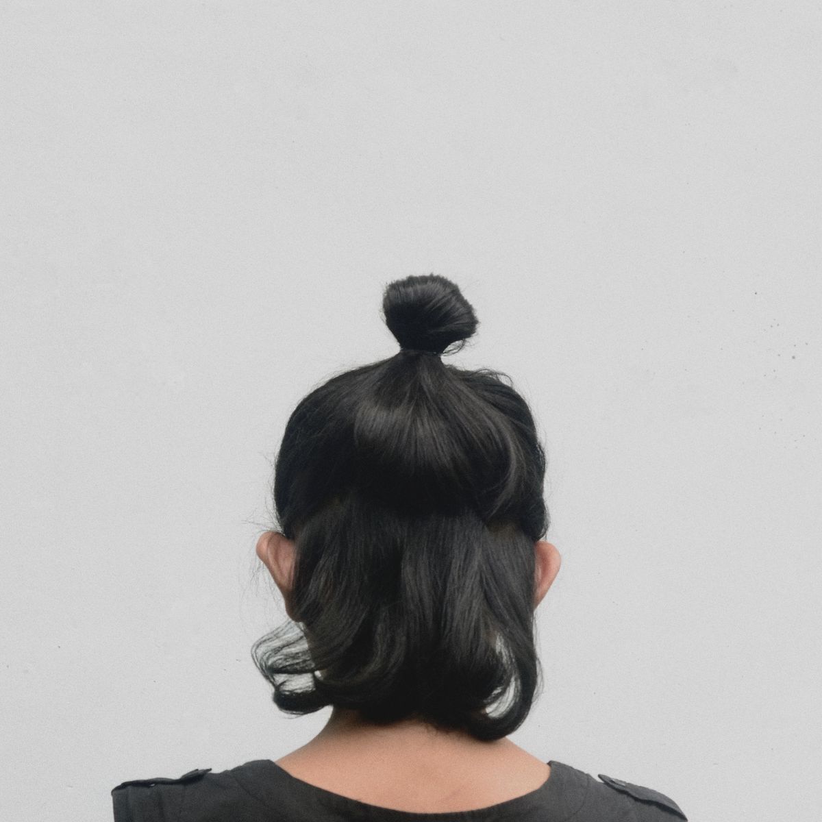 Woman with a sleek black hair bun styled at the back of her head