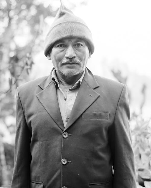 Grayscale Photo of an Elderly Man in Suit Jacket and Knit Cap