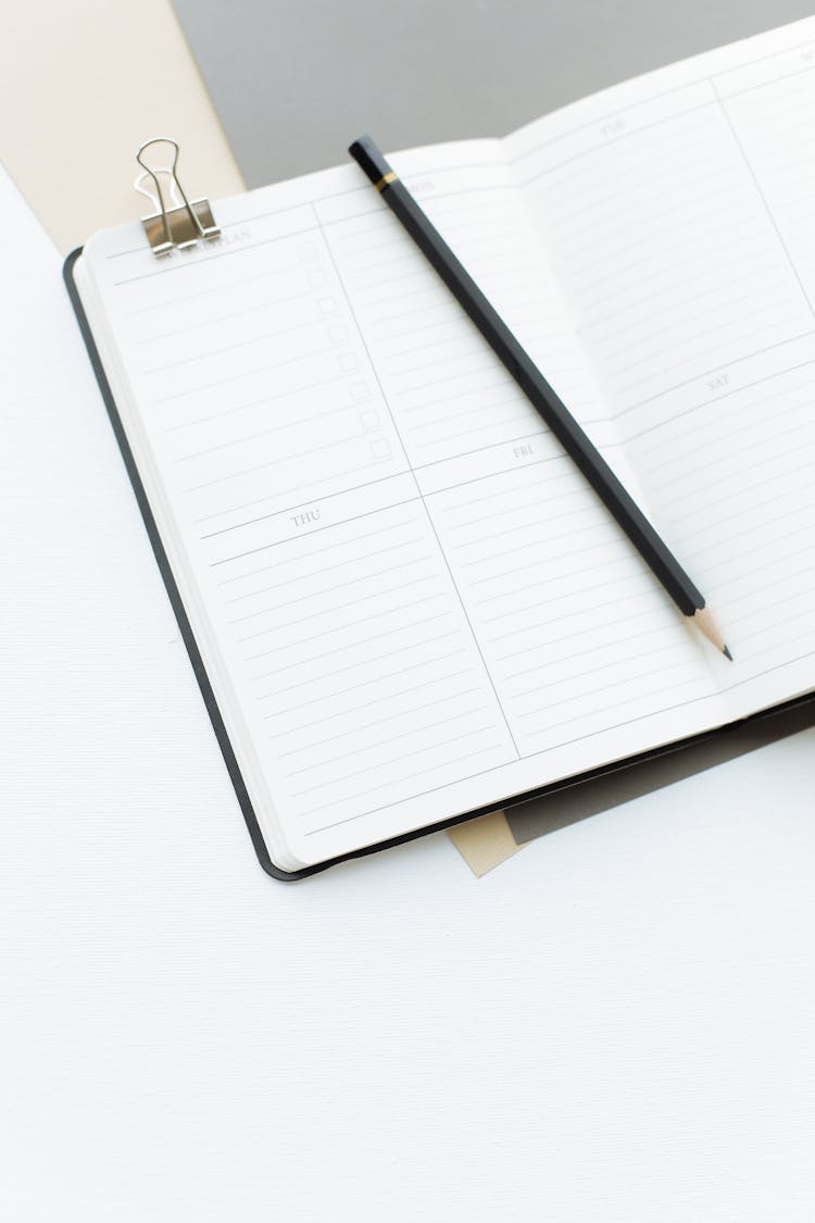 Opened Diary With Pencil Placed On Desk