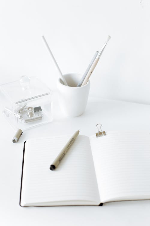 бесплатная Открытый блокнот с ручкой на белом столе Стоковое фото