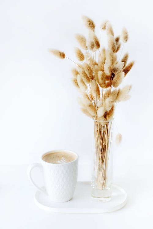一杯のコーヒーの近くに置かれた乾燥した植物の花束