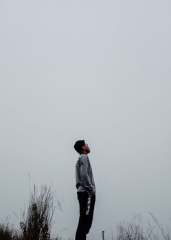 雾气蒙蒙的风景中，一名印度尼西亚男子站在户外，向上凝视
