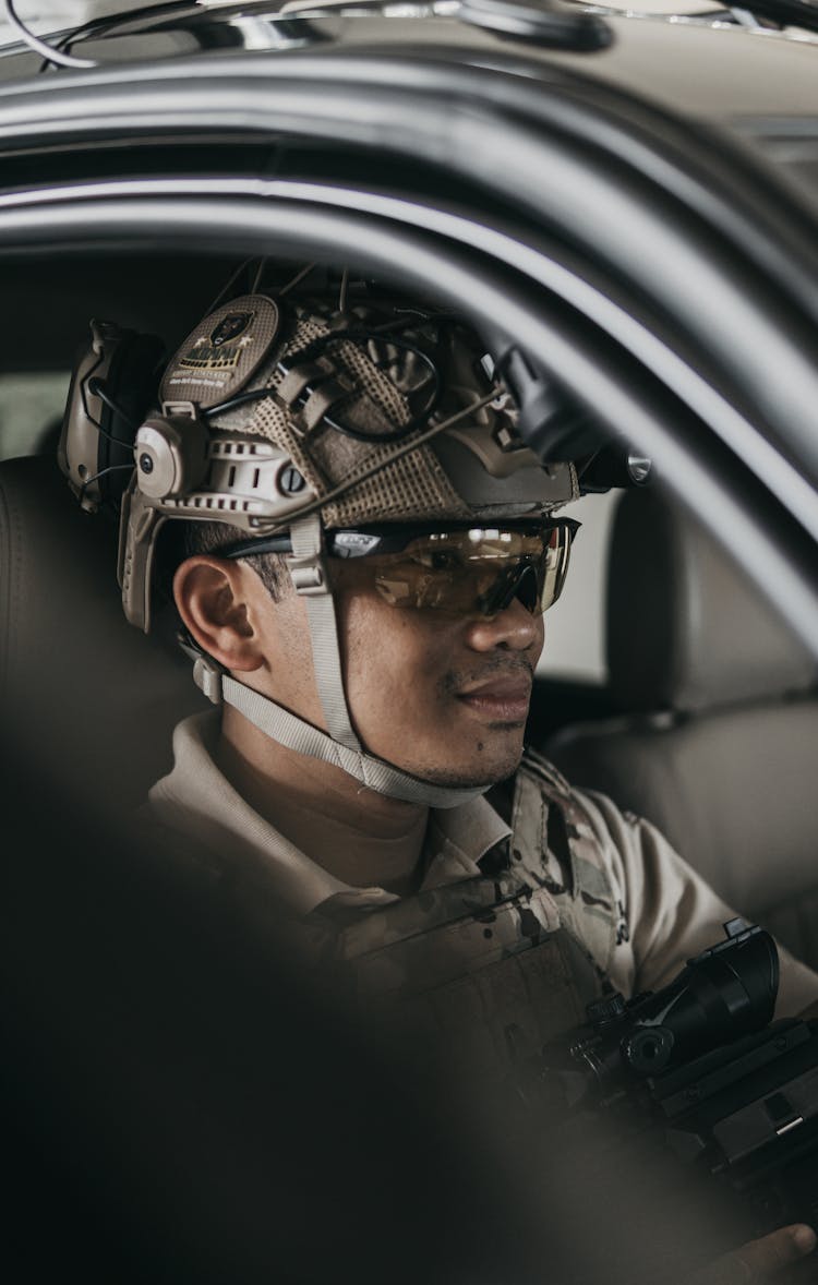 Man Wearing Military Protective Gears Sitting Inside A Vehicle