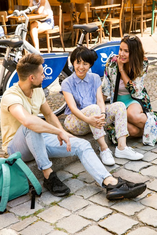 Free Friends Having a Conversation while Sitting on the Sidewalk Stock Photo