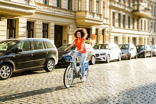 Free A Curly-Haired Woman in Orange Shirt Biking Stock Photo