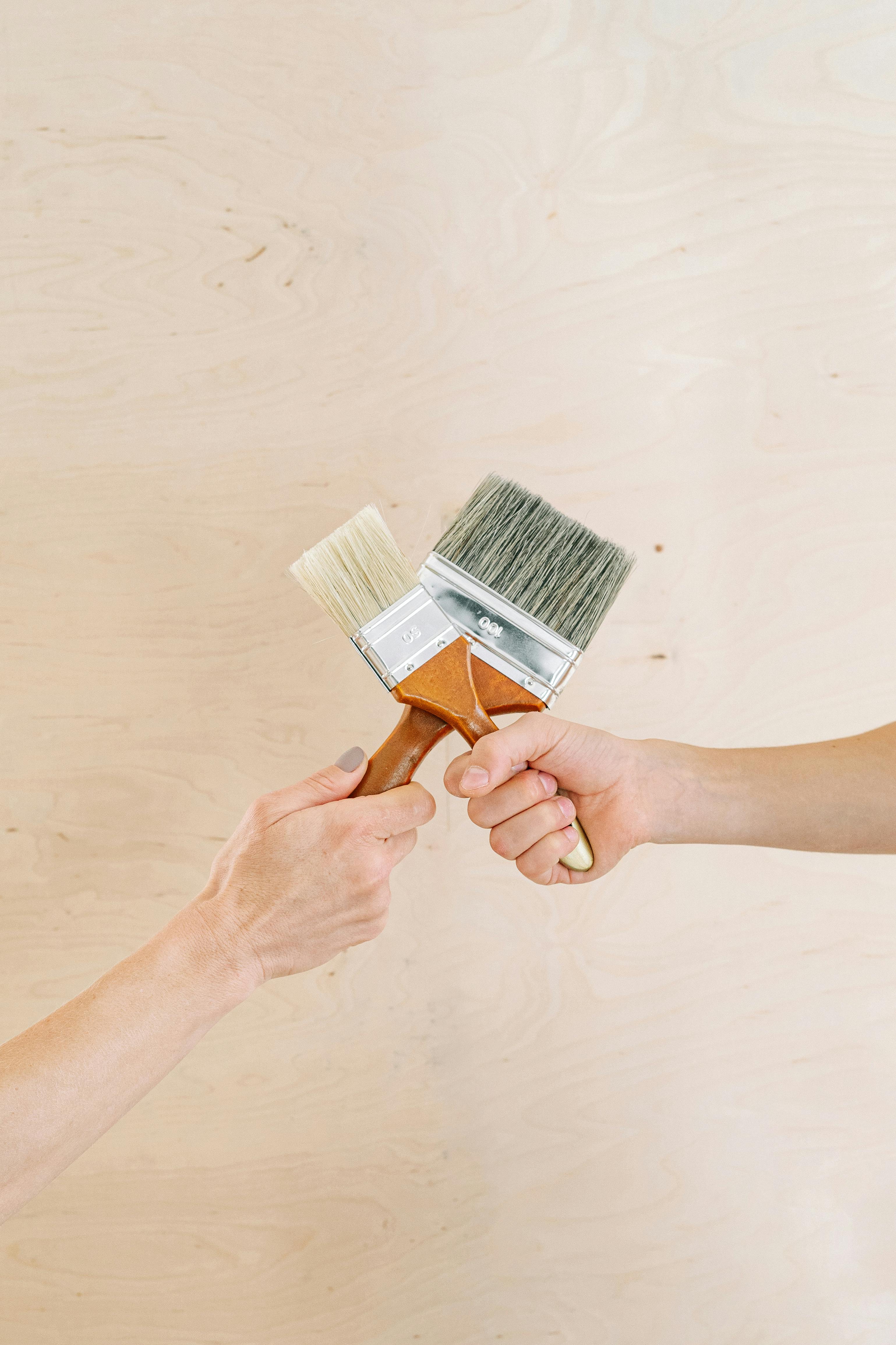 close up shot of two people holding paintbrushes