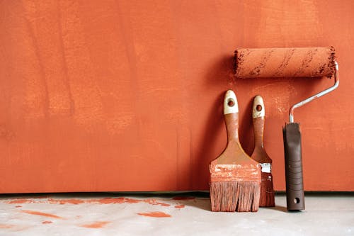 Close-Up Shot of Variety of Paintbrushes with Orange Paint