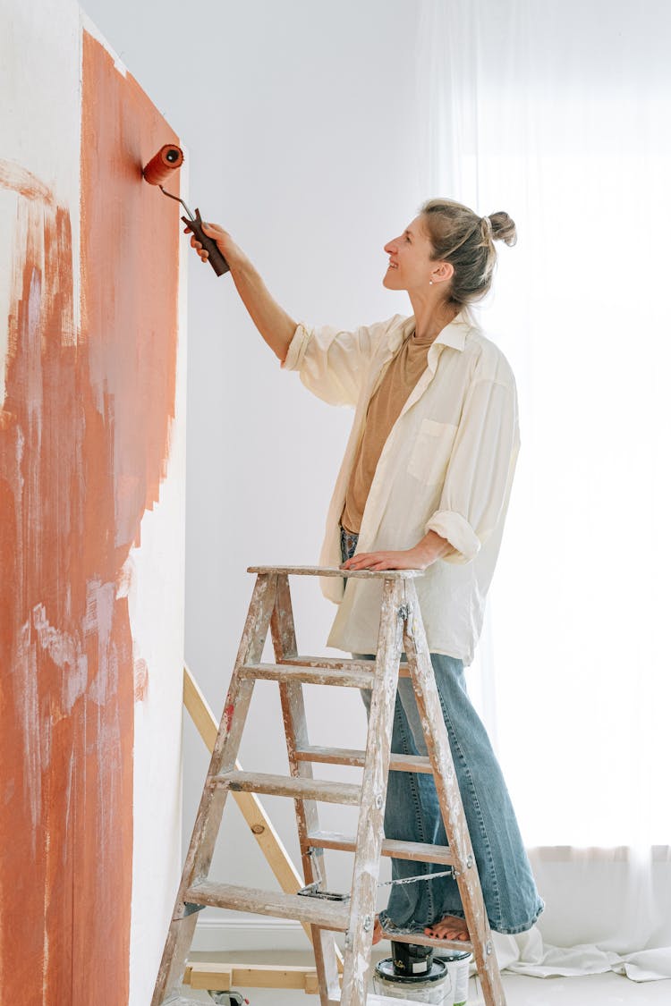 A Woman Painting Using A Paint Roller 